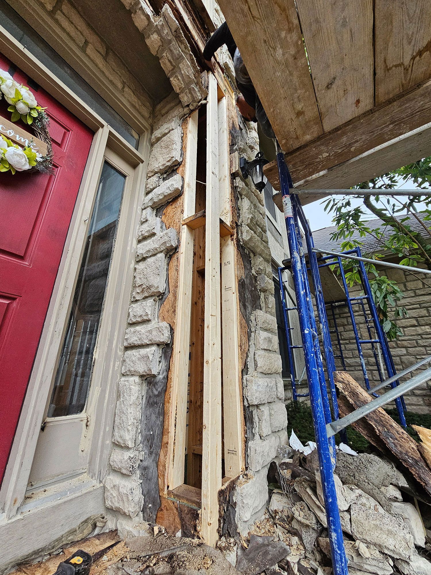 A stone wall with a red door is being remodeled