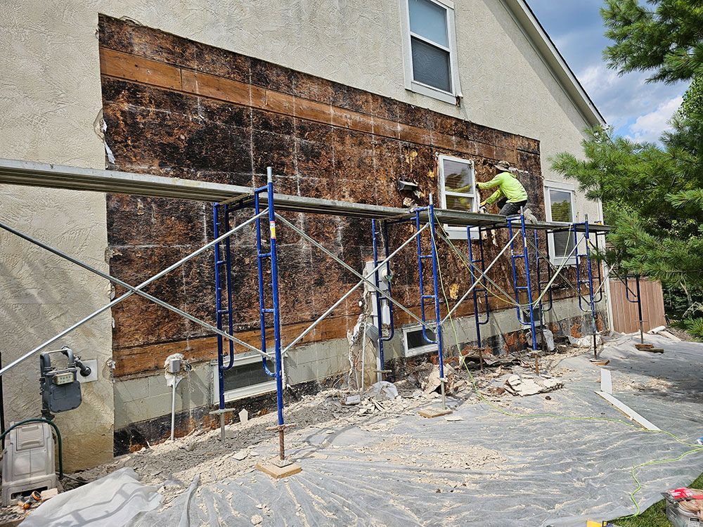 A man is working on the side of a house with scaffolding