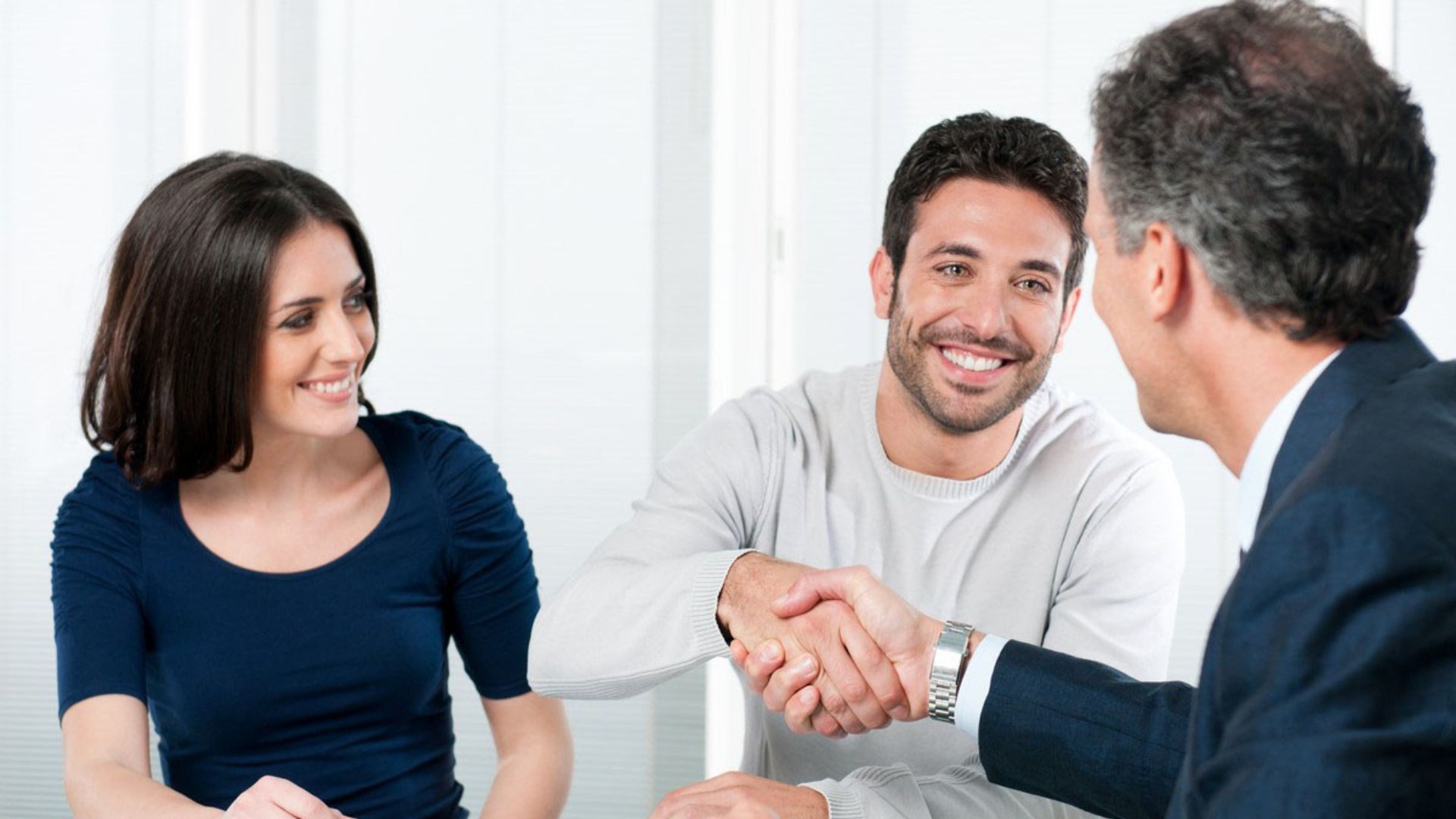 A man and a woman are shaking hands over a table.