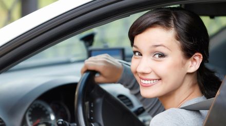 A woman is smiling while sitting in a car.