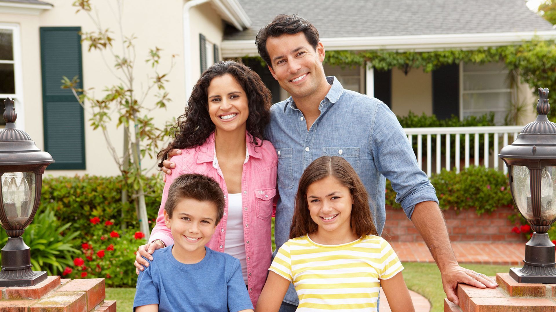 A family is posing for a picture in front of their house.