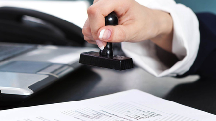 A person is stamping a piece of paper on a desk.