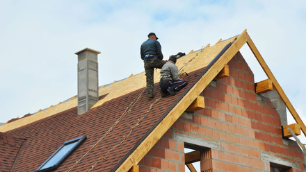 Two men are working on the roof of a house.