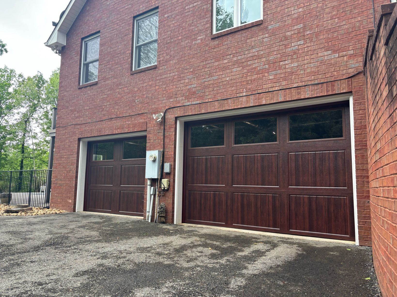 Brick house exterior with two dark garage doors and a paved driveway