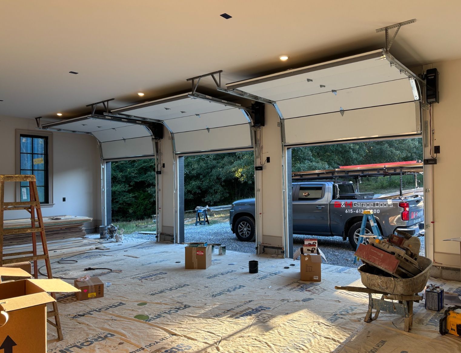 Partially renovated garage with open doors, construction debris, and a truck visible outside.