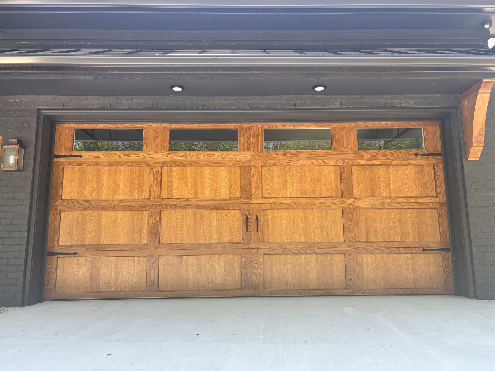 Wooden garage door with small windows under a dark roof overhang.