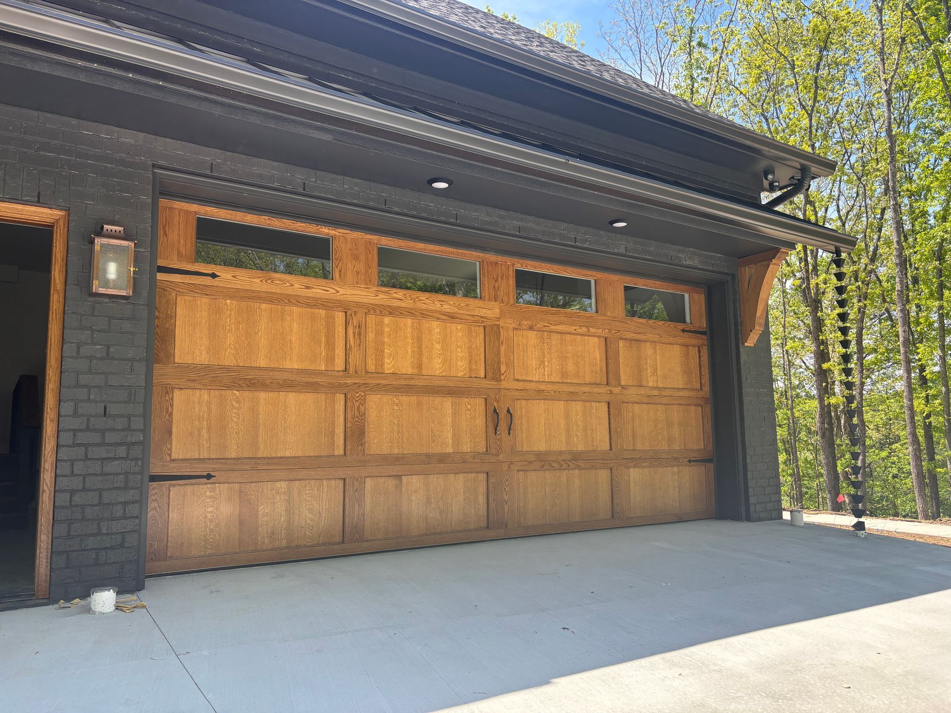 Wooden garage door on a modern home with a concrete driveway and trees beside it.