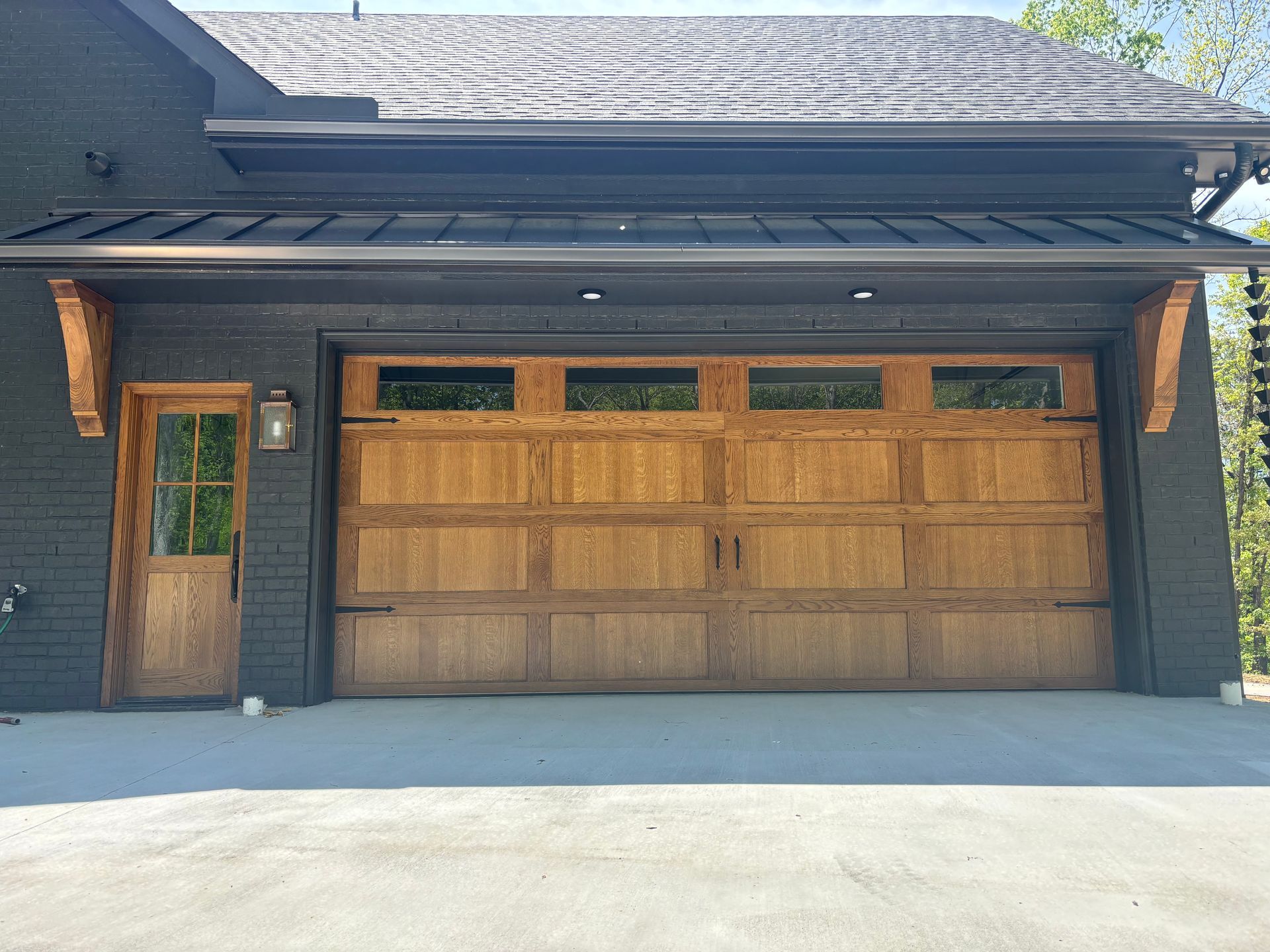 Modern house exterior with a wood garage door and front entry beneath a dark roof