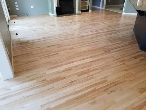 Empty room with light wood flooring and a white fireplace in the background