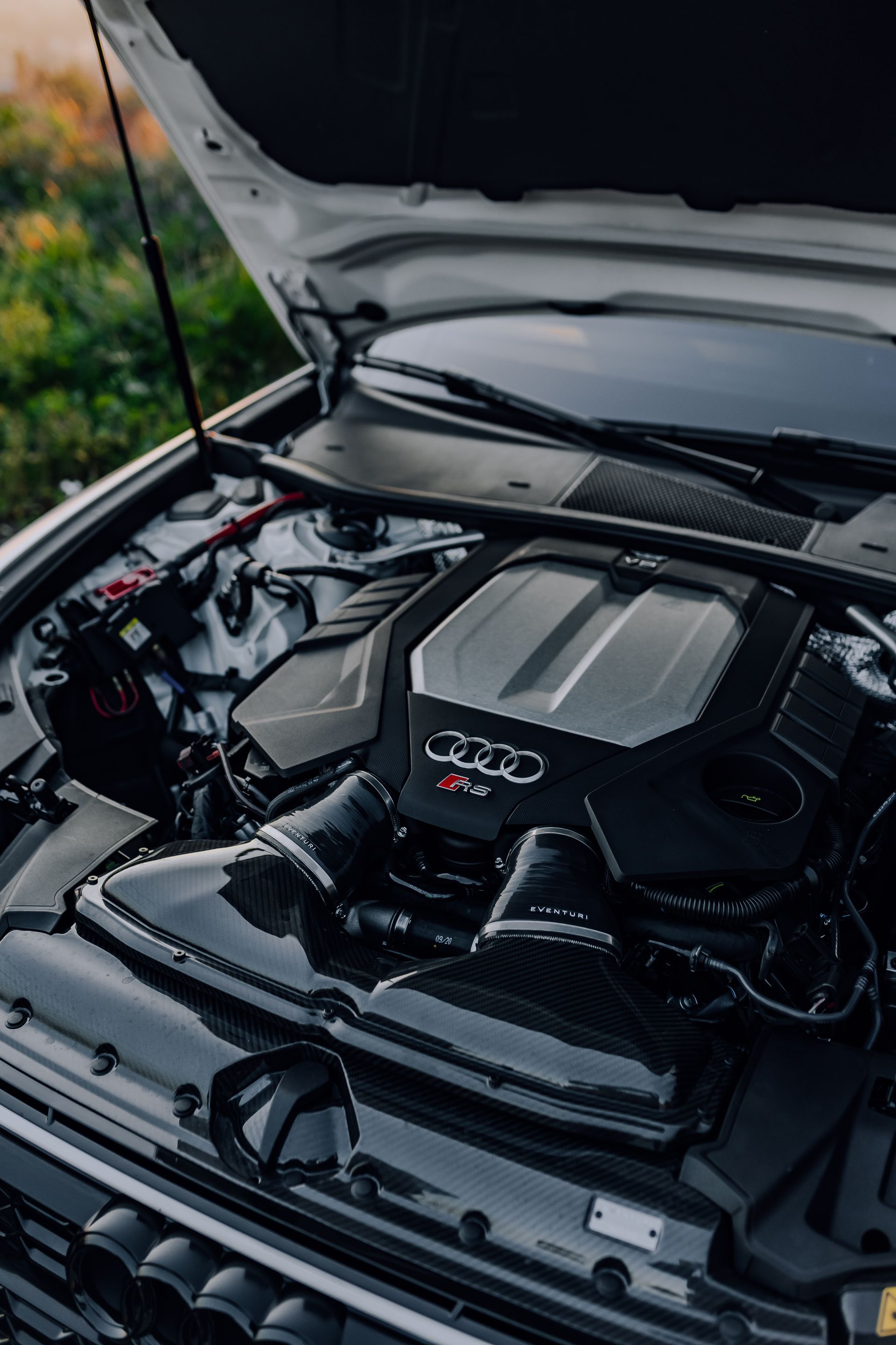 Open car hood showing a clean black engine bay with Mercedes-Benz AMG engine cover