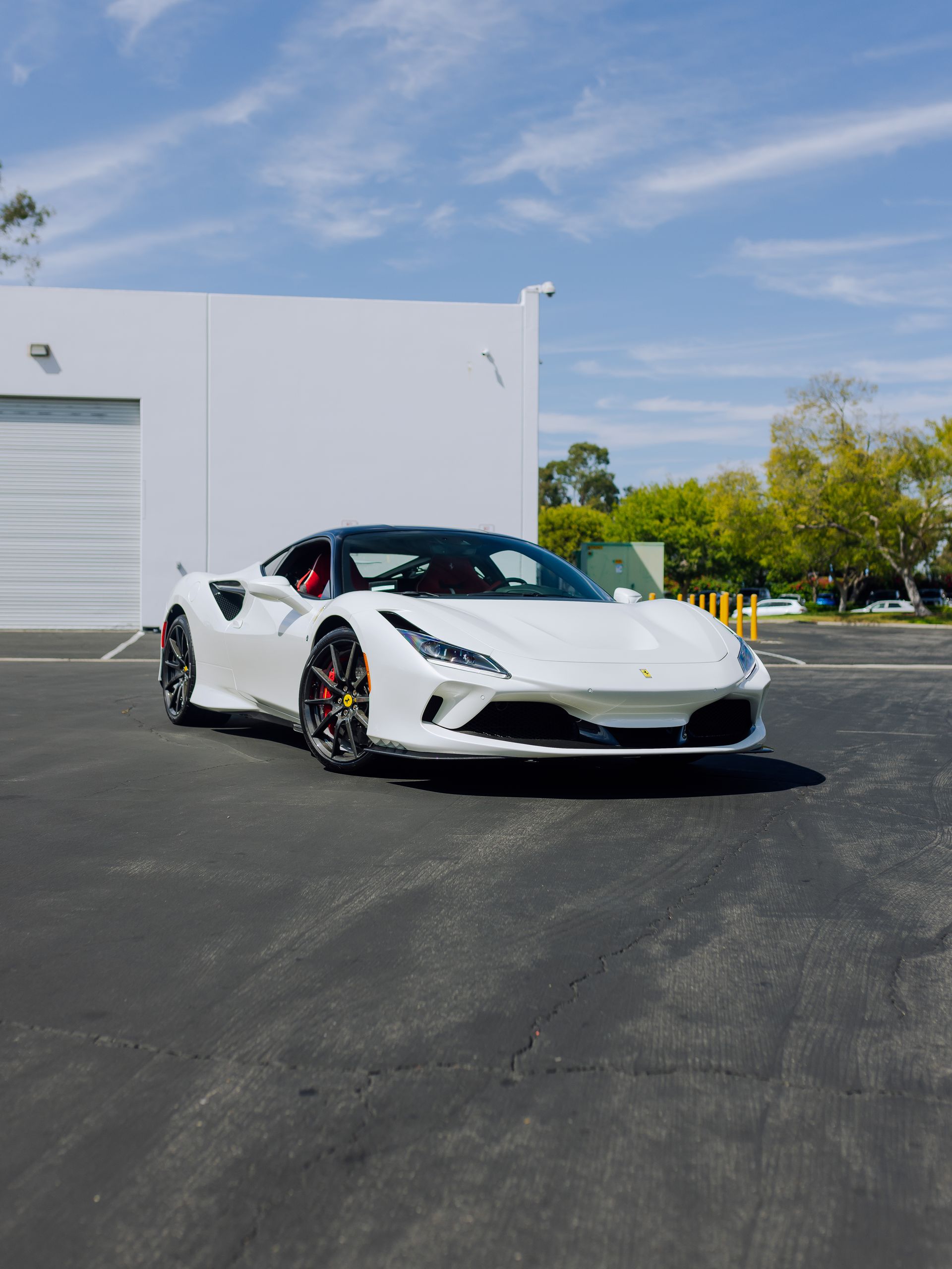 White sports car parked outside a white building on a sunny day.