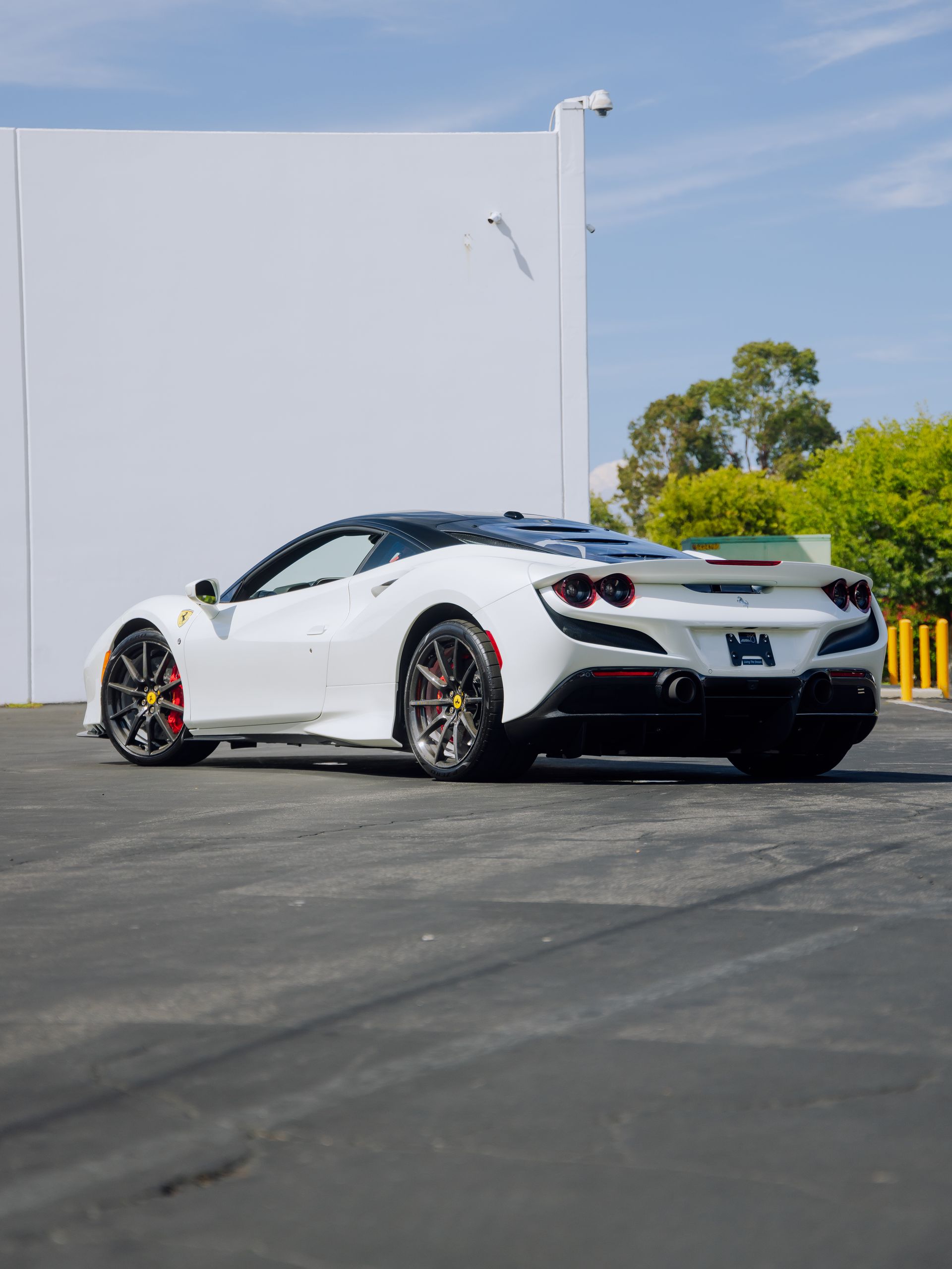White sports car parked on asphalt beside a white building under a clear sky