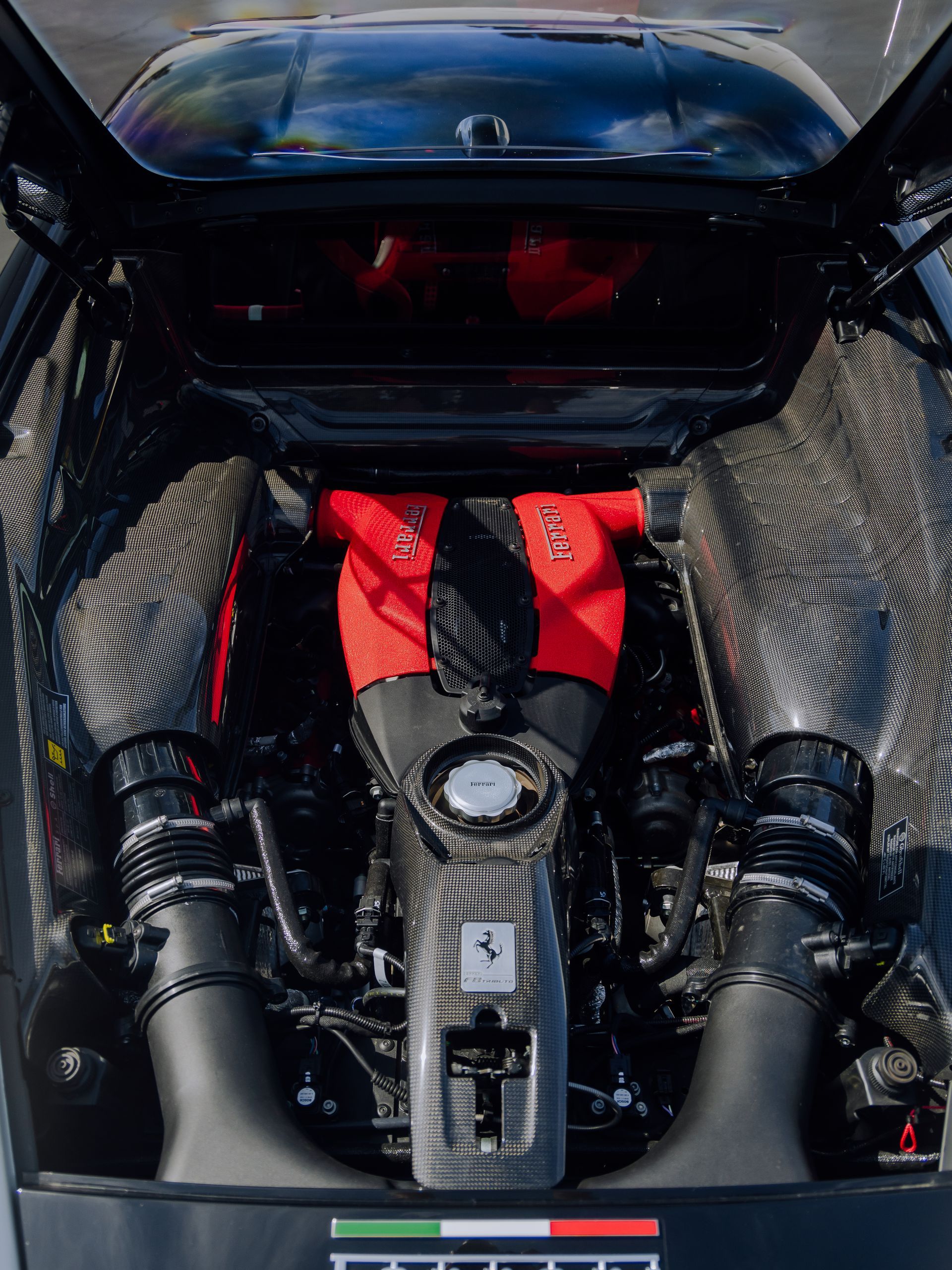 Open car engine bay with a red-and-black V8 engine on display