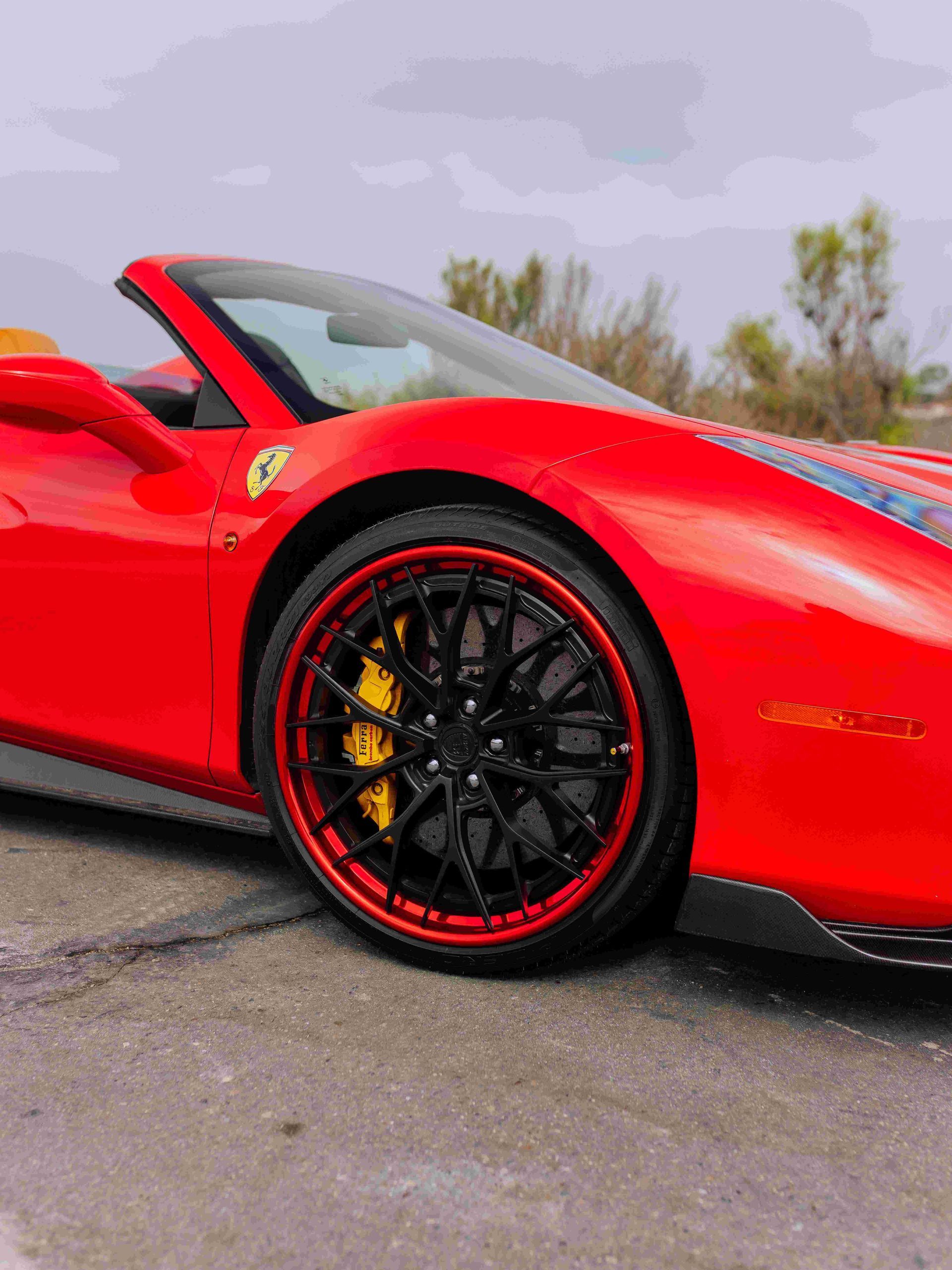 Red sports car convertible with black wheels parked on a wet road