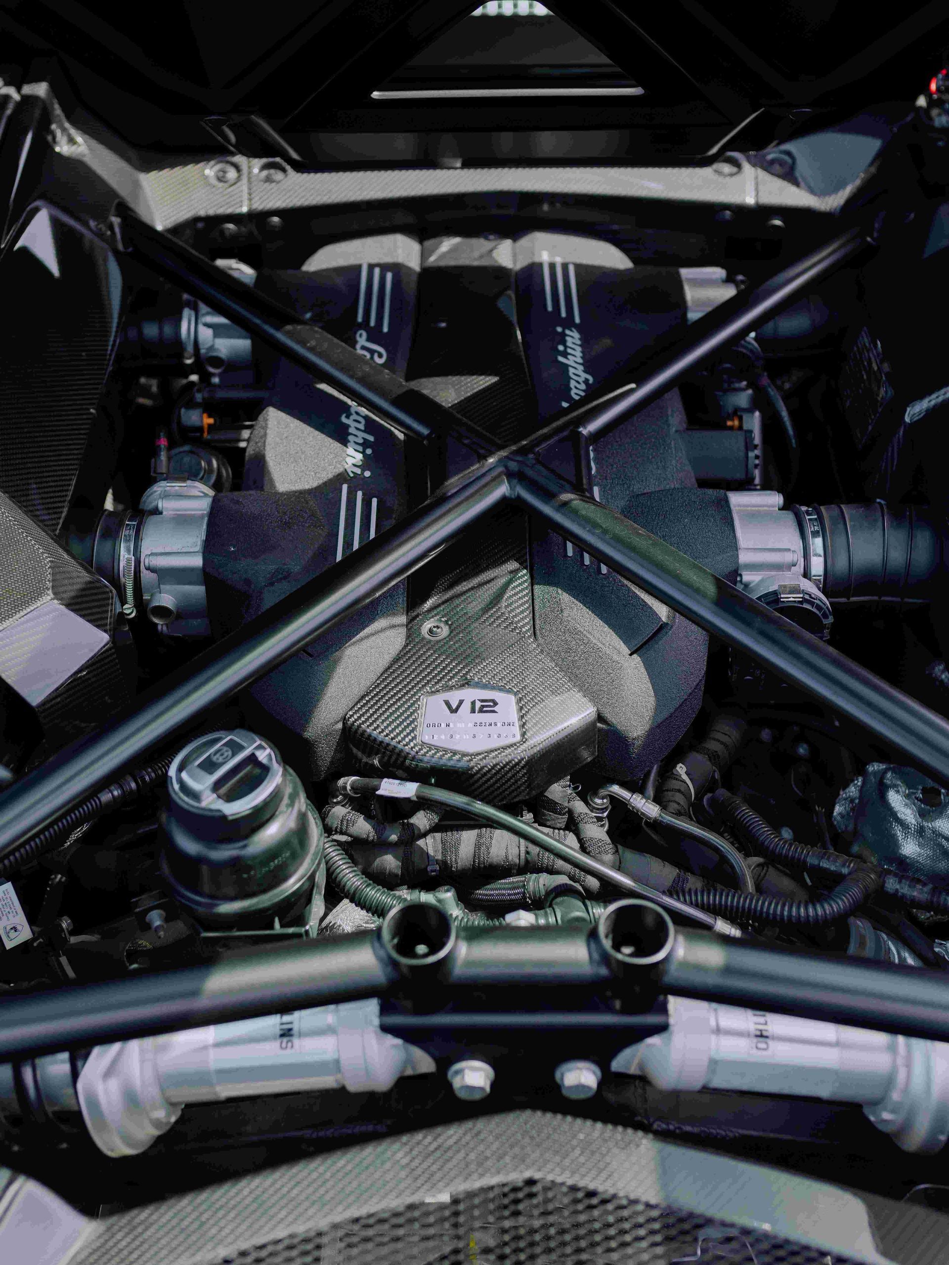 Racing car engine bay with visible turbo piping, cross braces, and exposed mechanical components