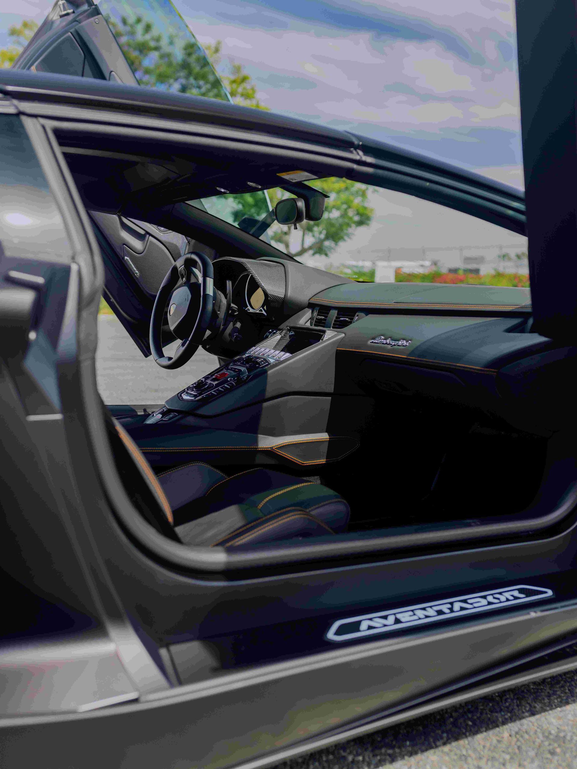 Open car door showing black leather interior and dashboard with sky visible outside