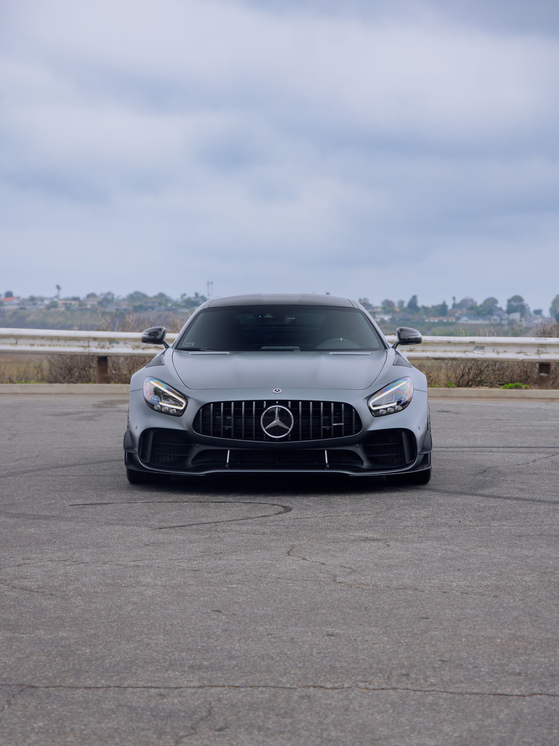 Front view of a black Mercedes-Benz parked on an empty road under a cloudy sky