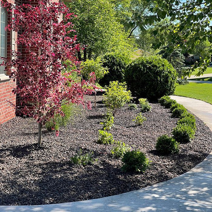 A brick house with a lush green lawn and trees in front of it.