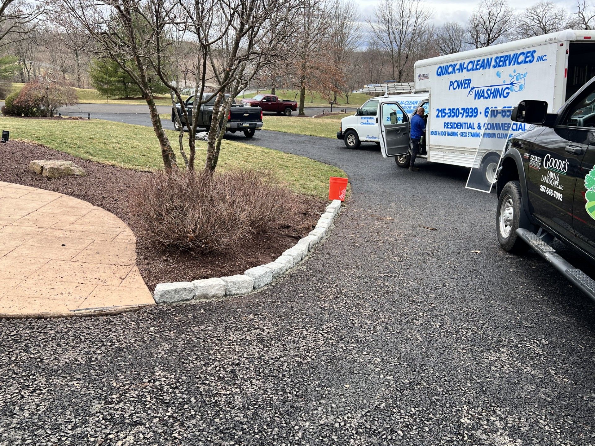 A white truck is parked in a driveway next to a black truck.