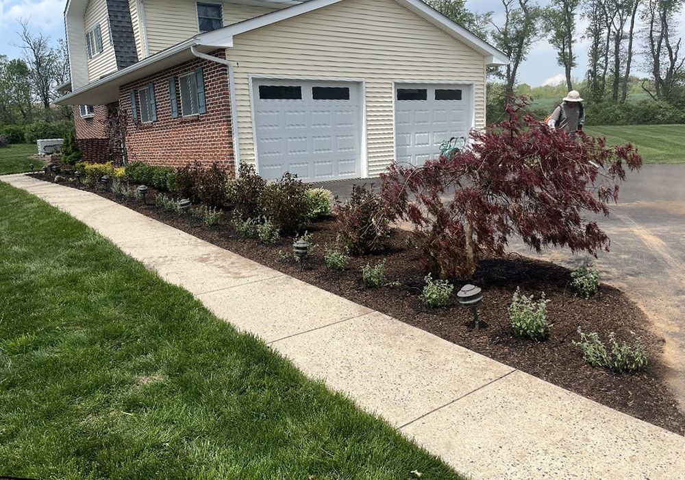 A house with two garage doors and a walkway leading to it.