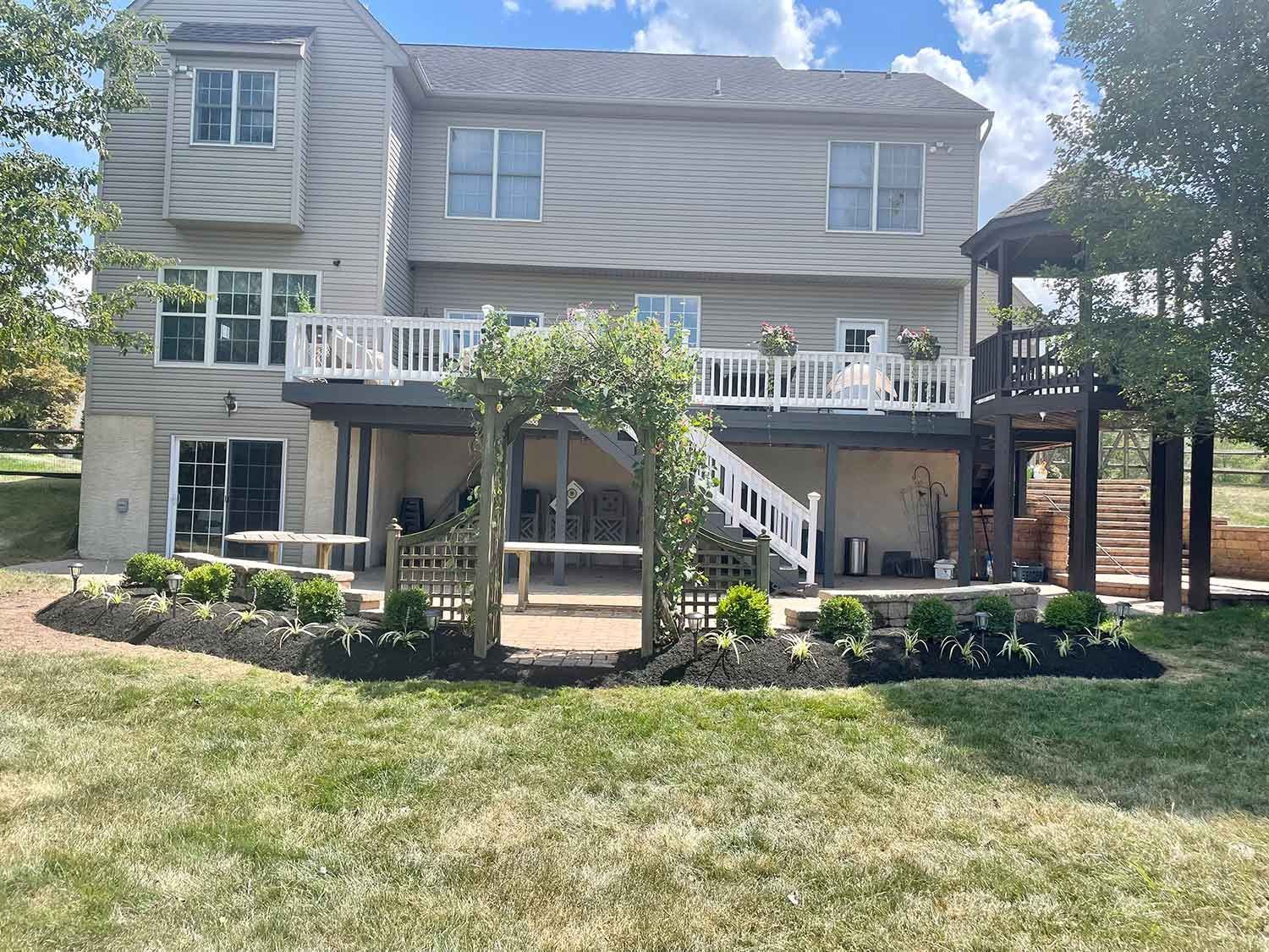 The back of a house with a large deck and stairs leading to it.