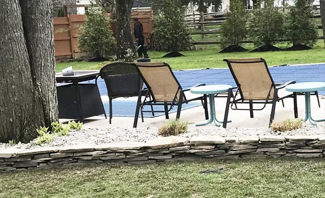 A row of chairs and tables in front of a swimming pool.