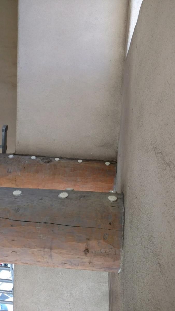 A wooden bench is sitting in a corner of a room next to a wall.