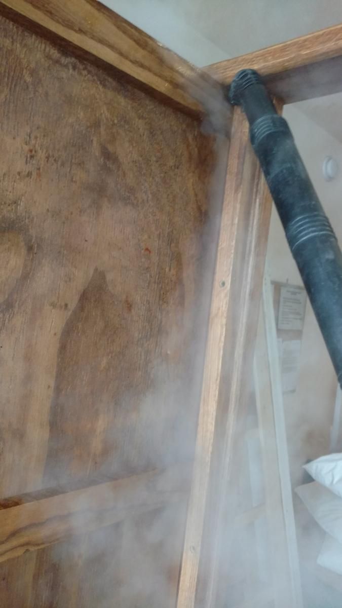 A vacuum cleaner is being used to clean a wooden wall.