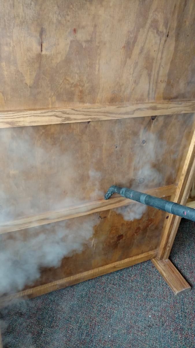 A person is using a vacuum cleaner to clean a wooden wall.