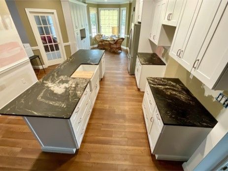 A kitchen with black granite counter tops and white cabinets.