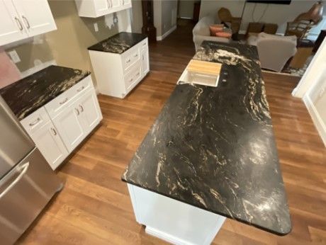 A kitchen with a black granite counter top and white cabinets