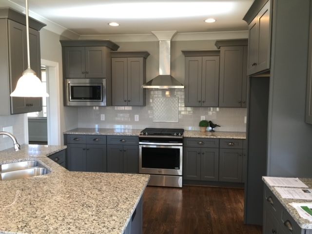 A kitchen with gray cabinets and granite counter tops