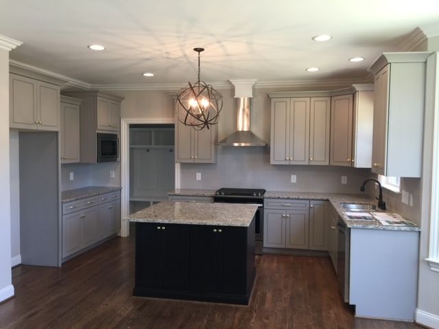 A kitchen with white cabinets and a black island