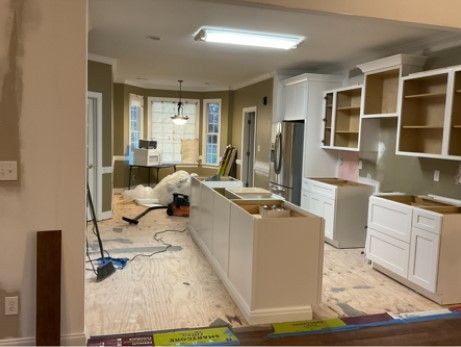 A kitchen is being remodeled with white cabinets and stainless steel appliances.
