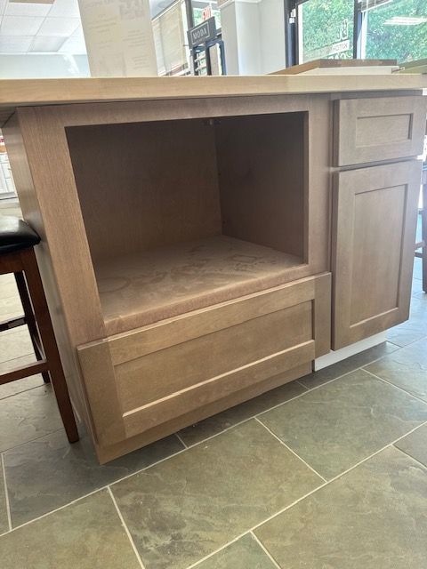 A wooden cabinet is sitting on a tiled floor in a kitchen.