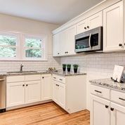 A kitchen with white cabinets , granite counter tops , stainless steel appliances and a sink.