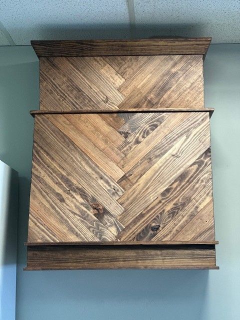 A wooden cabinet with a herringbone pattern is hanging on a wall.