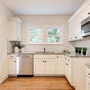 A kitchen with white cabinets , stainless steel appliances , a sink , and a microwave.