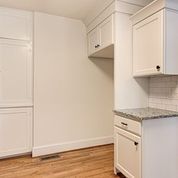 A kitchen with white cabinets , granite counter tops , and hardwood floors.