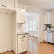 A kitchen with white cabinets and hardwood floors and a dishwasher.