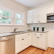 A kitchen with white cabinets , granite counter tops , stainless steel appliances , and hardwood floors.