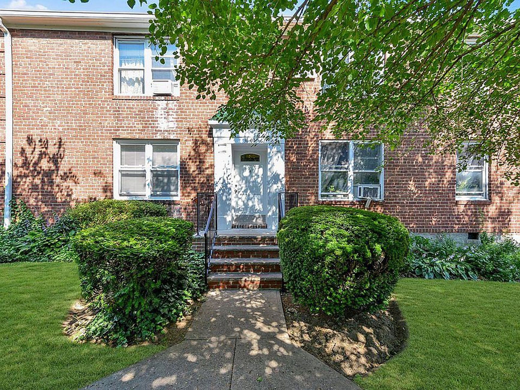 A brick apartment building with a walkway leading to the front door.
