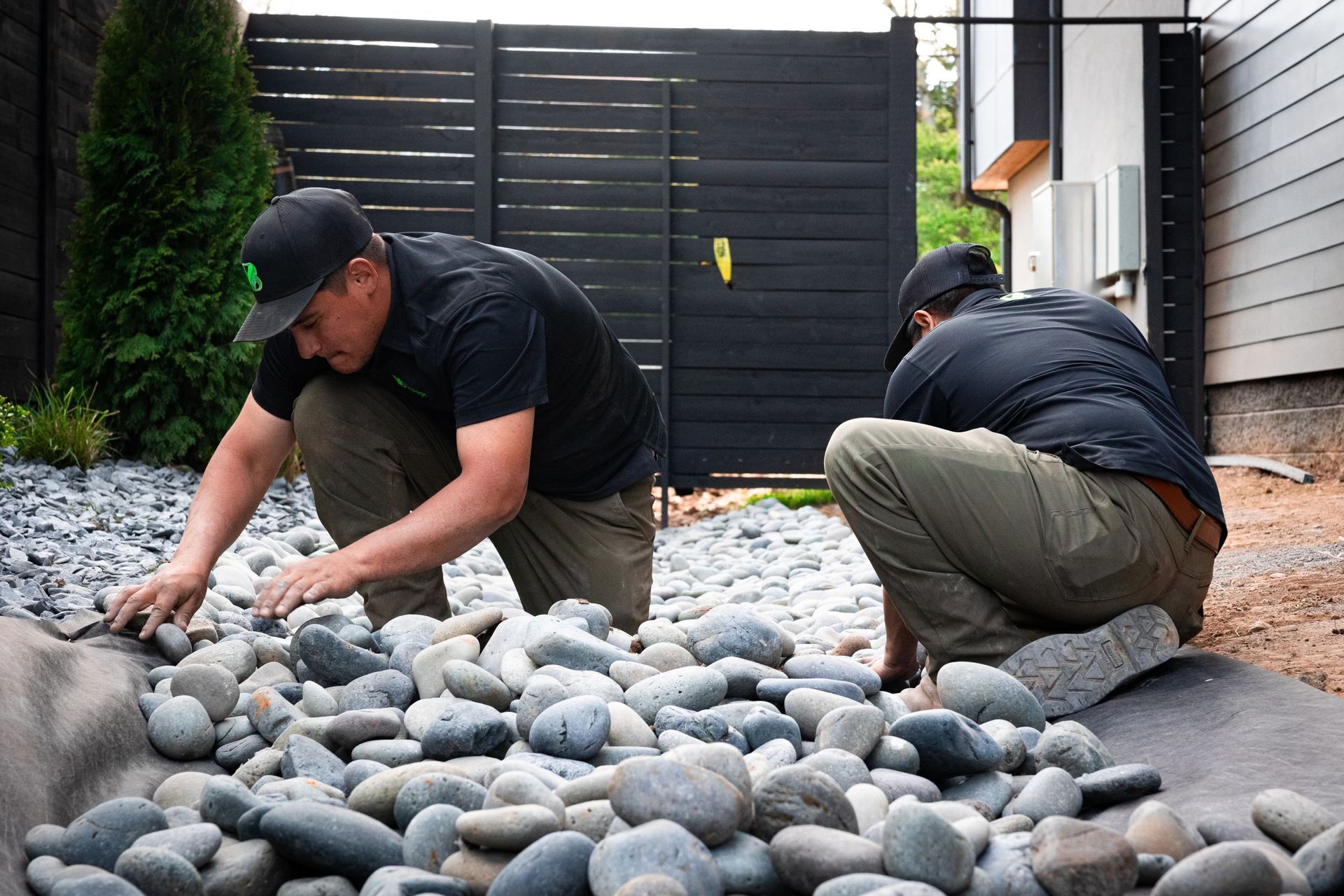 Two men are working on a pile of rocks in a yard