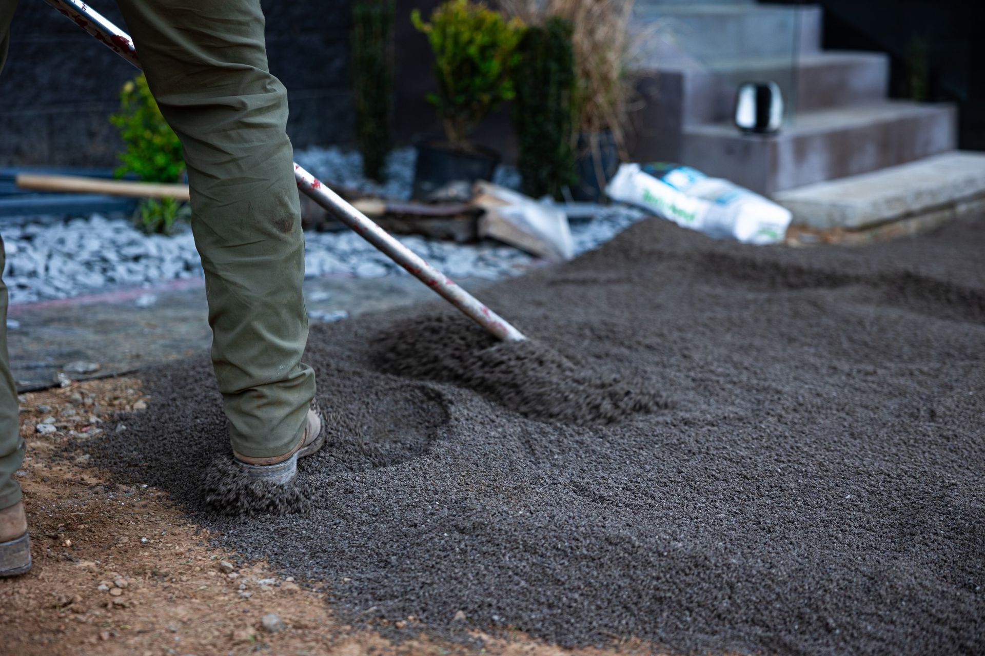 A person is raking dirt on the ground with a shovel
