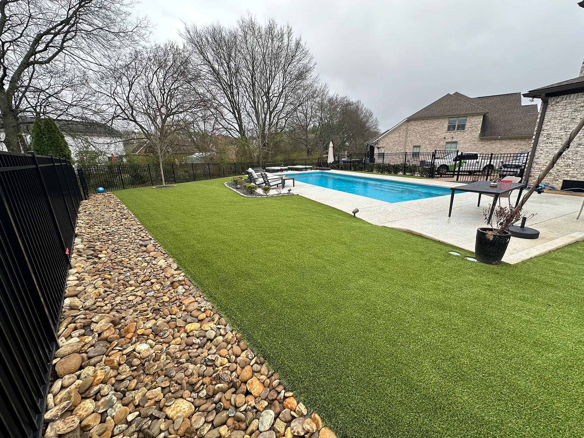 There is a large swimming pool in the backyard of a house