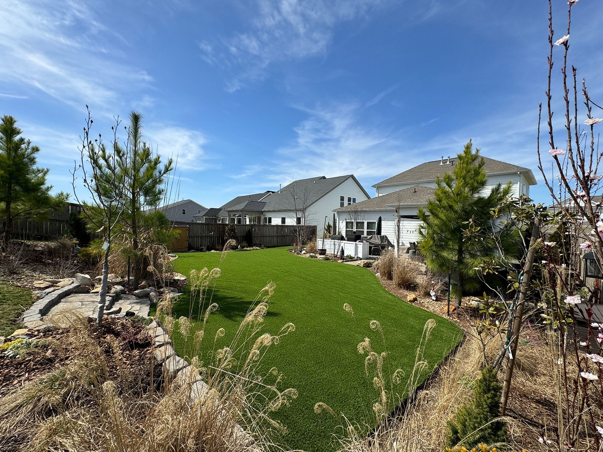 A large backyard with a lush green lawn and a house in the background