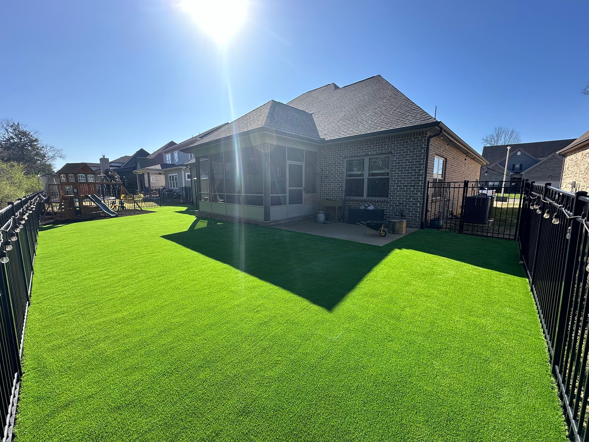 A large backyard with a black metal fence