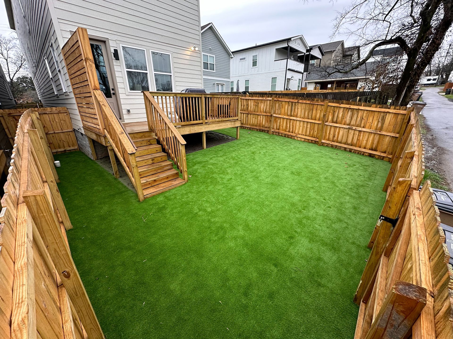 A backyard with a wooden deck and a wooden fence surrounding it