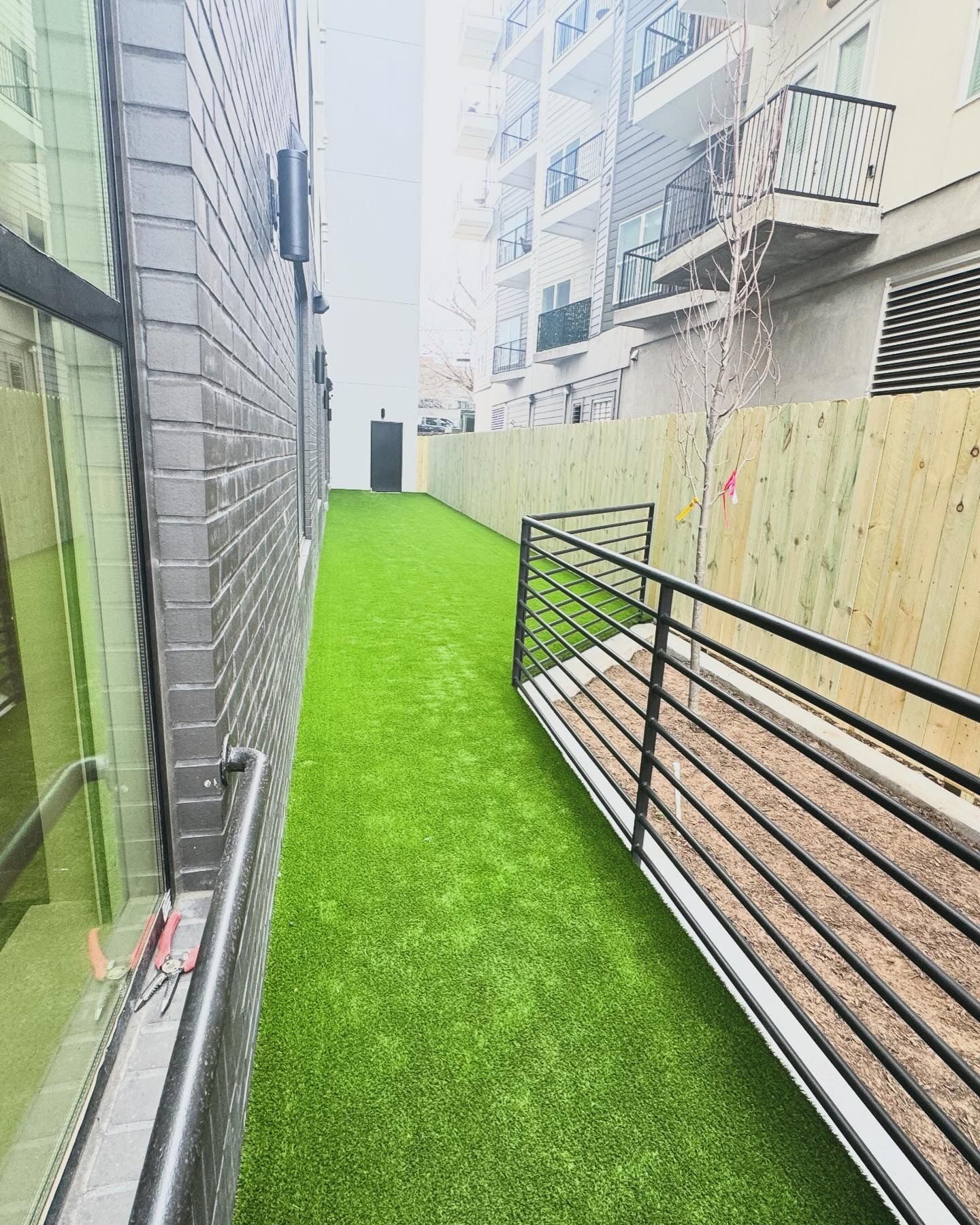 A walkway between two buildings with grass and a railing