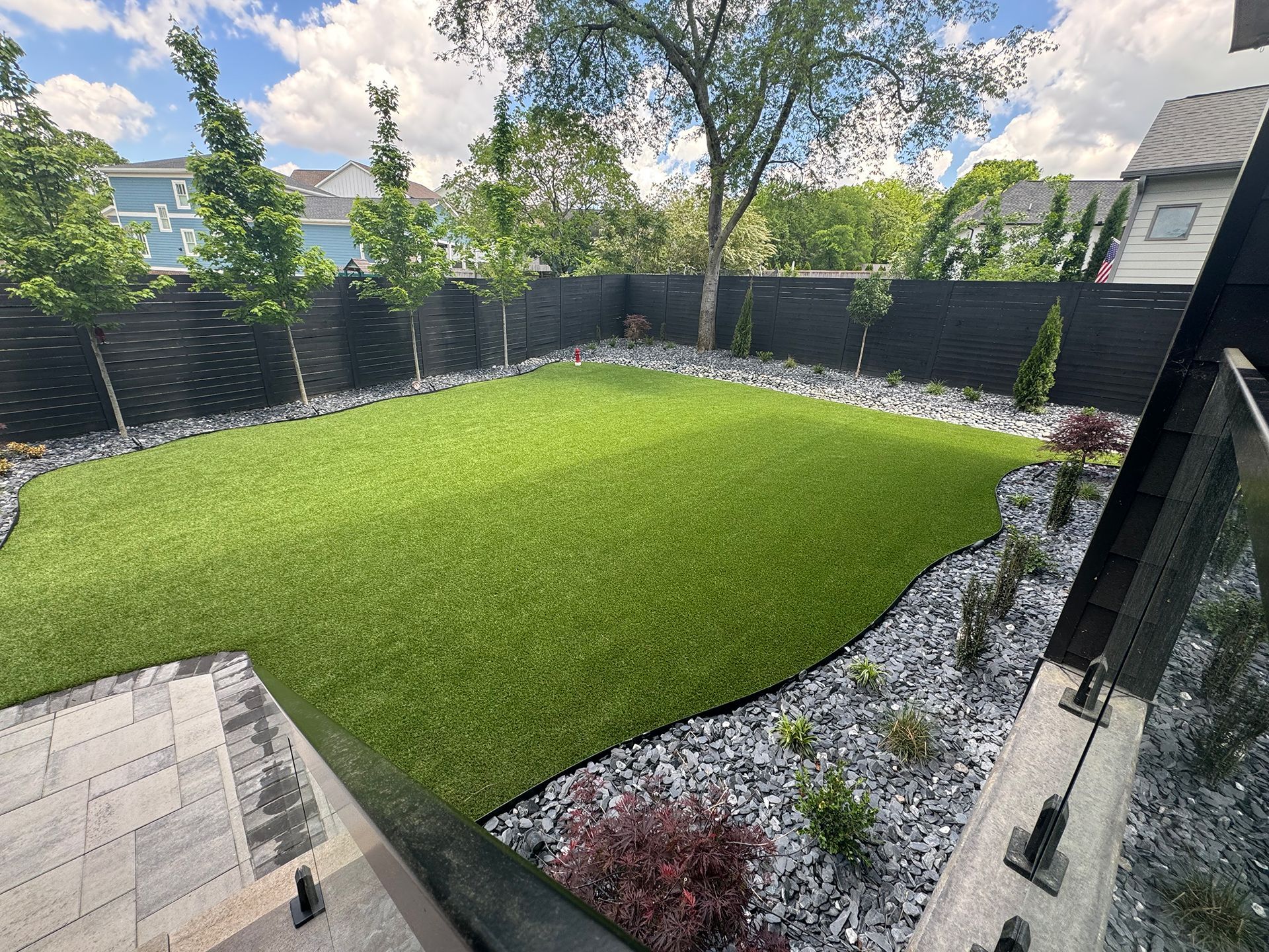 A backyard with a lush green lawn and a black fence
